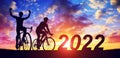 Silhouette of cyclists with bicycles at sunset. New Year 2022 concept. Royalty Free Stock Photo
