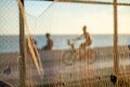 Silhouette of cyclists and people walking on the edge of a beach against sunset