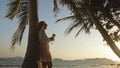 Woman drinking pineapple cocktail Pina Colada near palm tree, in Royalty Free Stock Photo