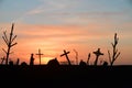 Silhouette of decayed graveyard with tilted crosses and tombstones in sunset light Royalty Free Stock Photo