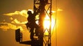 silhouette of a dedicated technician expertly navigating the height of a communication tower. Kitted out with safety gear and Royalty Free Stock Photo