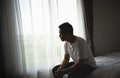 Silhouette depressed man sadly sitting on the bed in the bedroom. Sad asian men suffering depression insomnia awake and sit alone Royalty Free Stock Photo