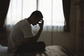 Silhouette depressed man sadly sitting on the bed in the bedroom. Sad asian men suffering depression insomnia awake and sit alone Royalty Free Stock Photo