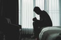 Silhouette depressed man sadly sitting on the bed in the bedroom. Sad asian man suffering depression insomnia awake and sit alone
