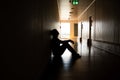 Silhouette of depressed man sitting on walkway of residence building. Sad man, Cry, drama, lonely and unhappy concept Royalty Free Stock Photo