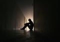 Silhouette of depressed man sitting on walkway of residence building.