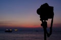 Silhouette of digital camera on tripod with sunset sky at sea bl Royalty Free Stock Photo
