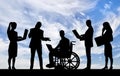 Silhouette of a disabled man in a wheelchair and his work team during a work process Royalty Free Stock Photo