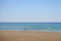 Silhouette of a distant anonymous tourist on the background of the sea on the sandy coast near the wavy sea during the