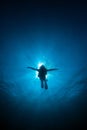Silhouette diver sunrays behind at Underwater blue background i