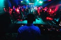 Silhouette of DJ playing music on mixer and a lot of people dancing in nightclub on stage