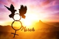 Silhouette of dove holding branch in 8th March text and Venus symbol shape flying on sunset sky Royalty Free Stock Photo