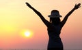 The silhouette of a dreamy girl looking up at the horizon. woman watching the sunset by the sea Raise your hand to welcome the Royalty Free Stock Photo