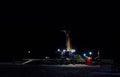 Silhouette of a drilling rig and drilling an oil and gas well in the deep night under the light of lanterns reflected on the white