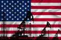 Silhouette of drilling rigs and oil derricks on the background of the flag of US. Oil and gas industry. The concept of oil fields