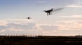 A silhouette of a drone rapidly moving towards an departing aircraft near a airport.