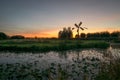 Silhouette of a dutch pumping mill and trees with twilight colors just after sunset Royalty Free Stock Photo