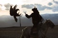 Silhouette of the Eagle Hunter traditional clothing, while hunting to the hare with a golden eagle in desert mountain