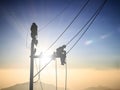 Silhouette electrical workers are installing high voltage system