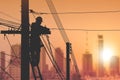 Silhouette electrician is installing cable lines to connecting internet signal on electric power pole in sunset time