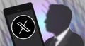 Silhouette of Elon Musk and the new Twitter logo on a smartphone screen