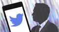 Silhouette of Elon Musk next to the phone with the Twitter logo on a gradient grunge background