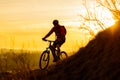 Silhouette of Enduro Cyclist Riding the Mountain Bike on the Rocky Trail at Sunset. Active Lifestyle Concept. Space for Text. Royalty Free Stock Photo