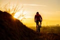 Silhouette of Enduro Cyclist Riding the Mountain Bike on the Rocky Trail at Sunset. Active Lifestyle Concept. Space for Text. Royalty Free Stock Photo