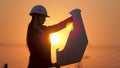 Silhouette of an engineer looks at the project of construction of a high-voltage power plant. The engineer is reading Royalty Free Stock Photo