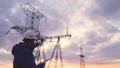 Silhouette of engineer standing on field with electricity towers. Electrical engineer with high voltage electricity Royalty Free Stock Photo