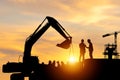 Silhouette of Engineer and worker checking project at building site background, construction site at sunset in evening time Royalty Free Stock Photo