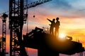 Silhouette of Engineer and worker checking project at building site background, construction site at sunset in evening time Royalty Free Stock Photo