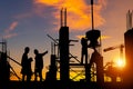 Silhouette of Engineer and worker team checking project at building site background, construction site with sunset in evening time Royalty Free Stock Photo