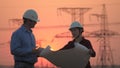 Silhouette of engineers looks at the construction of high-voltage power. Teams engineer looking discussing plan. Two Royalty Free Stock Photo