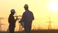 Silhouette of engineers looks at the construction of high-voltage power. Teams engineer looking discussing plan. Two Royalty Free Stock Photo