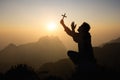 Silhouette of faithful man praying with Christian cross at sunset as concept for religion, faith, prayer and spirituality Royalty Free Stock Photo