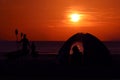 Silhouette family camping and kayaking on the beach with red sky sunset