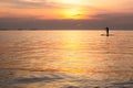 Silhouette of family playing the stand-up paddle board on the sea with beautiful summer sunset colors. Happy family concept