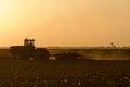 Silhouette of farmer tilling his land after the harvest.