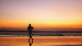 Silhouette of fat man runs along the beach during amazing sunset. Royalty Free Stock Photo