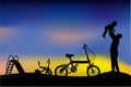 Silhouette of father have fun with his children, slide, tricycle and folding bike at park when sunset or sunrise