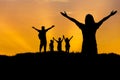 Silhouette father and mother and children standing raised hands up on sunset