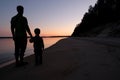 Silhouette of father and son holding hands, standing on the beach at sunset. Family on vacation. Calm water, tranquil weather, Royalty Free Stock Photo