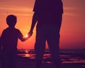 Silhouette of father and son holding hands at sunset sea Royalty Free Stock Photo