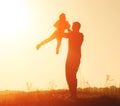 Silhouette of father throwing up his daughter in the sky at sunset