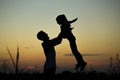 Silhouette of father throwing up his happy daughter in the air at sunset. Royalty Free Stock Photo