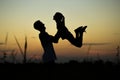 Silhouette of father throwing up his happy daughter in the air at sunset. Royalty Free Stock Photo