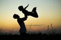 Silhouette of father throwing up his happy daughter in the air at sunset. Royalty Free Stock Photo