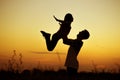 Silhouette of father throwing up his happy daughter in the air at sunset. family time togehter Royalty Free Stock Photo