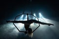 Silhouette of female Aerial acrobat on circus stage with spot lights on background